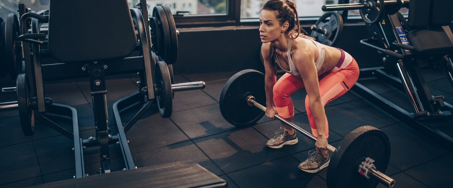 athletic woman doing barbell deadlifts at the gym