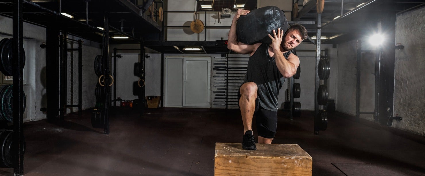 strong man doing step-up exercise with weight on shoulder