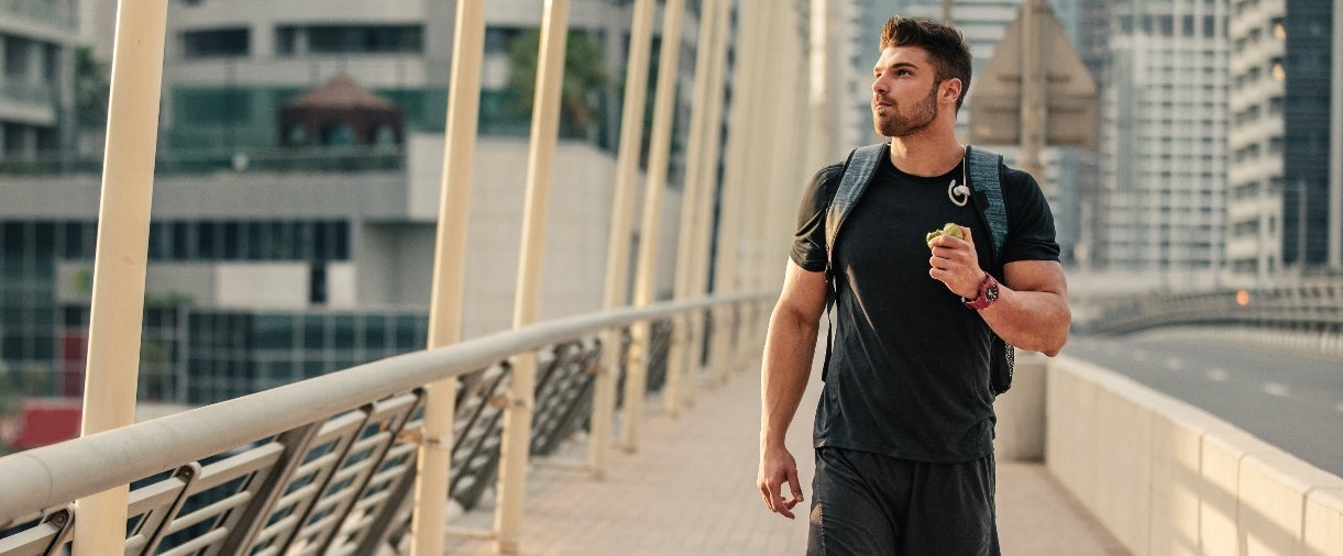 protein travel: young man eating walking across bridge
