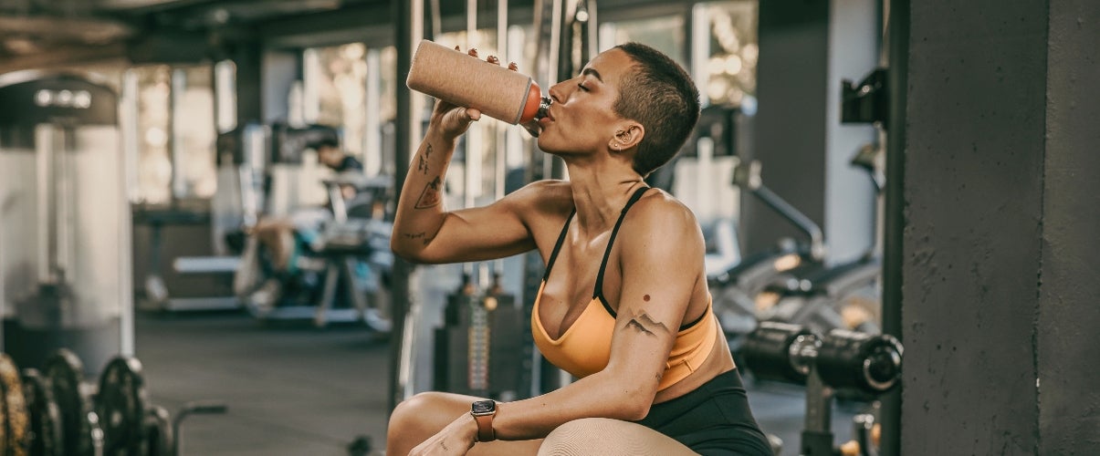 peptides: fit woman drinking at the gym