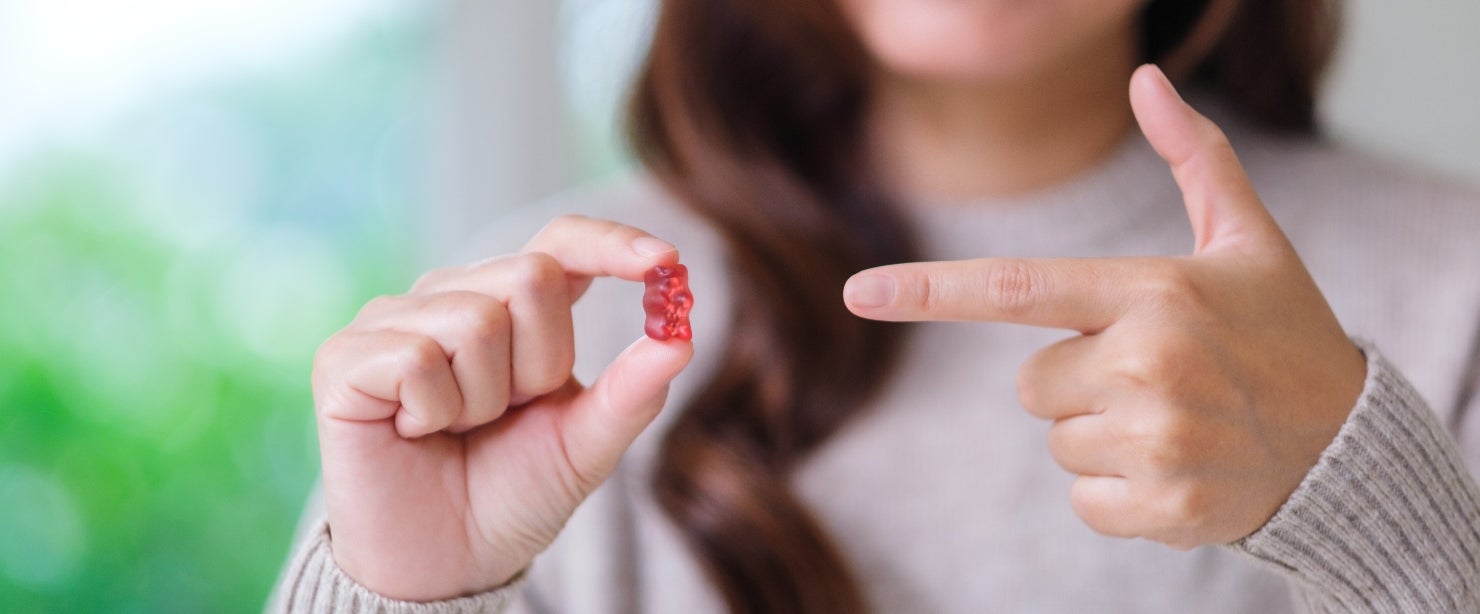 Woman holding gummy bear | Supplements that taste like candy